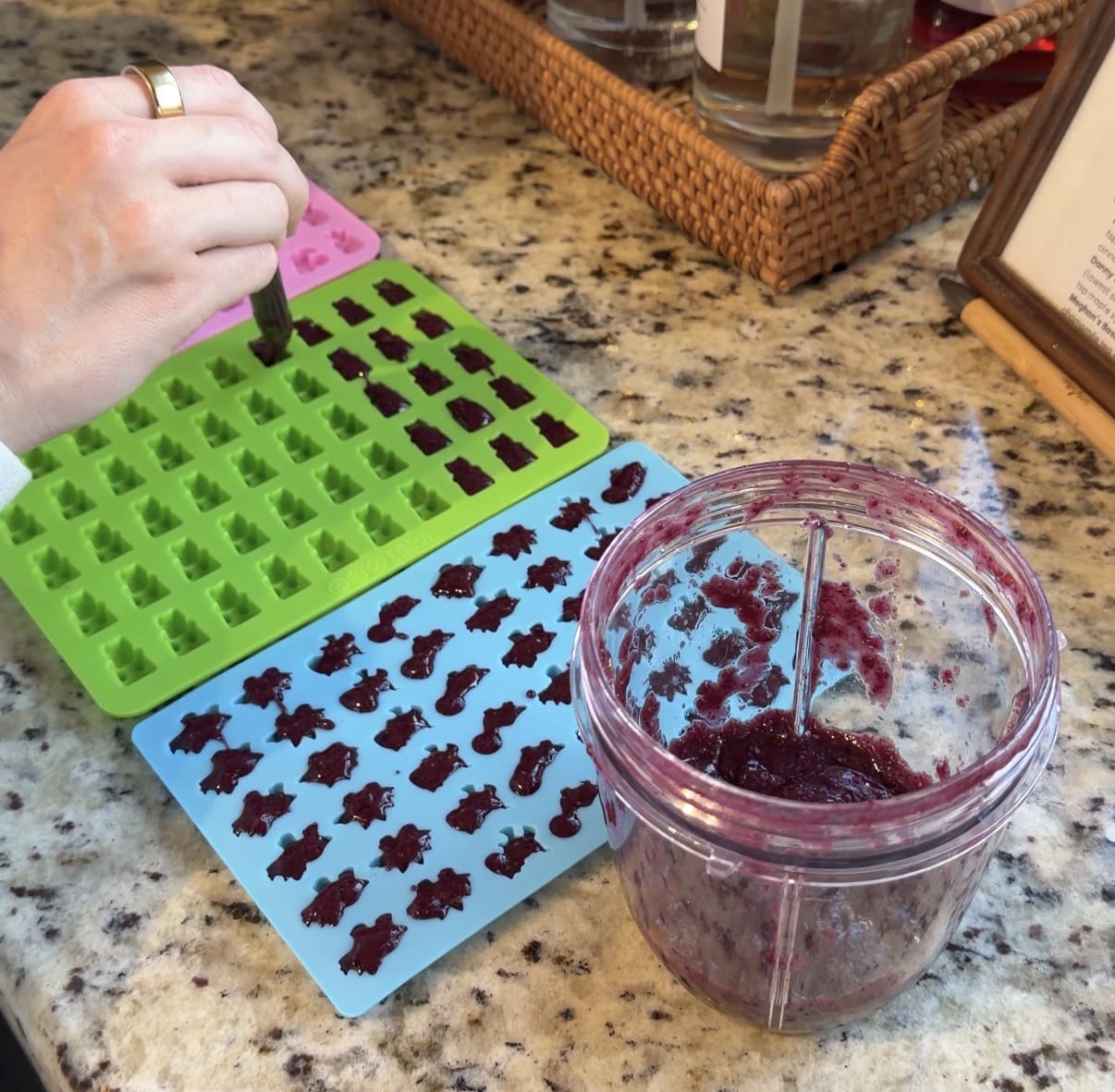 Filling silicone molds with homemade fruit snacks mixture using a dropper