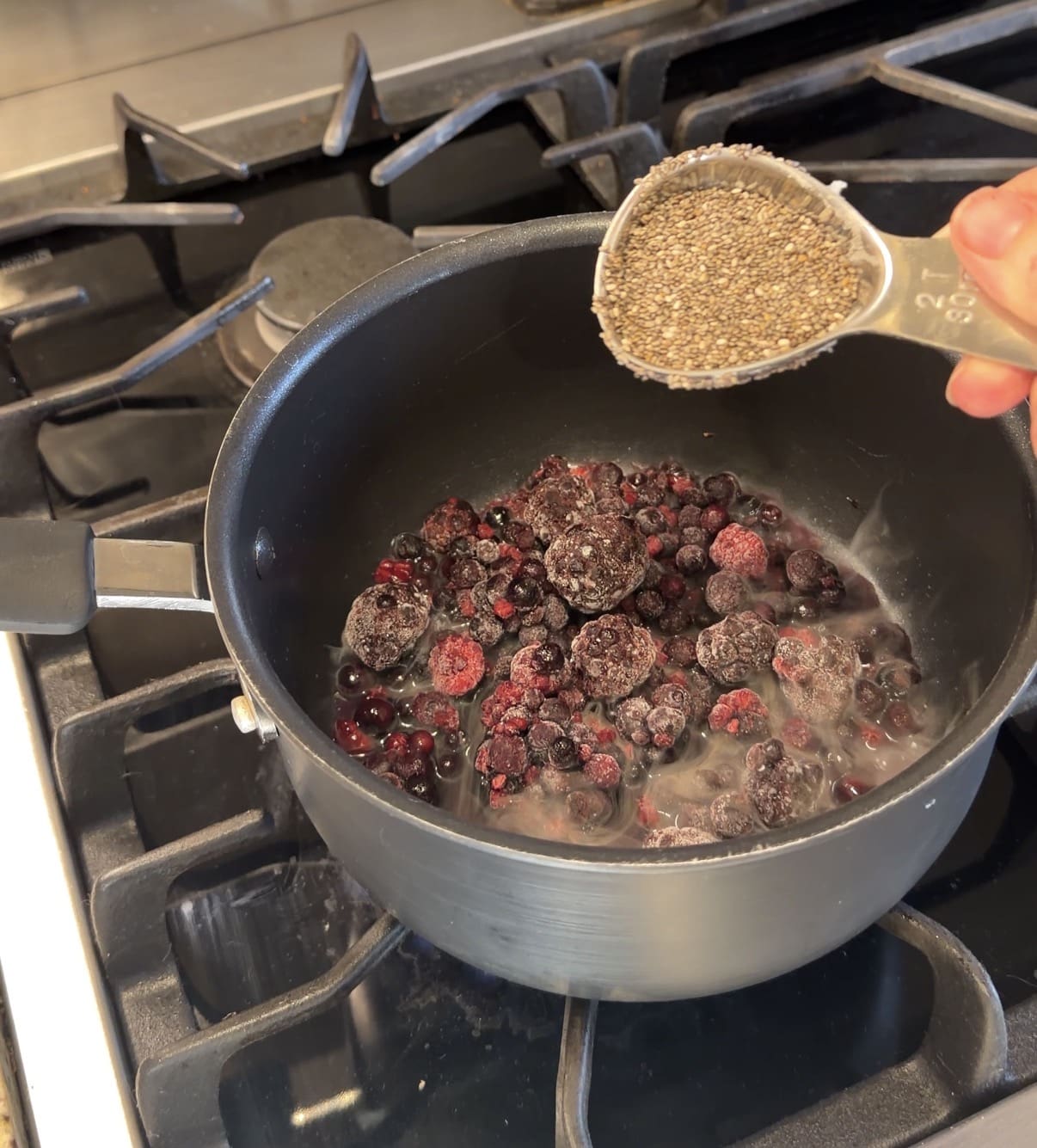Making homemade fruit snacks - frozen berries simmering in a pot with chia seeds